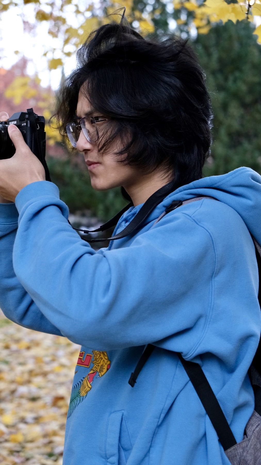 Close-up candid of Jerry Pan photographing in a blue hoodie