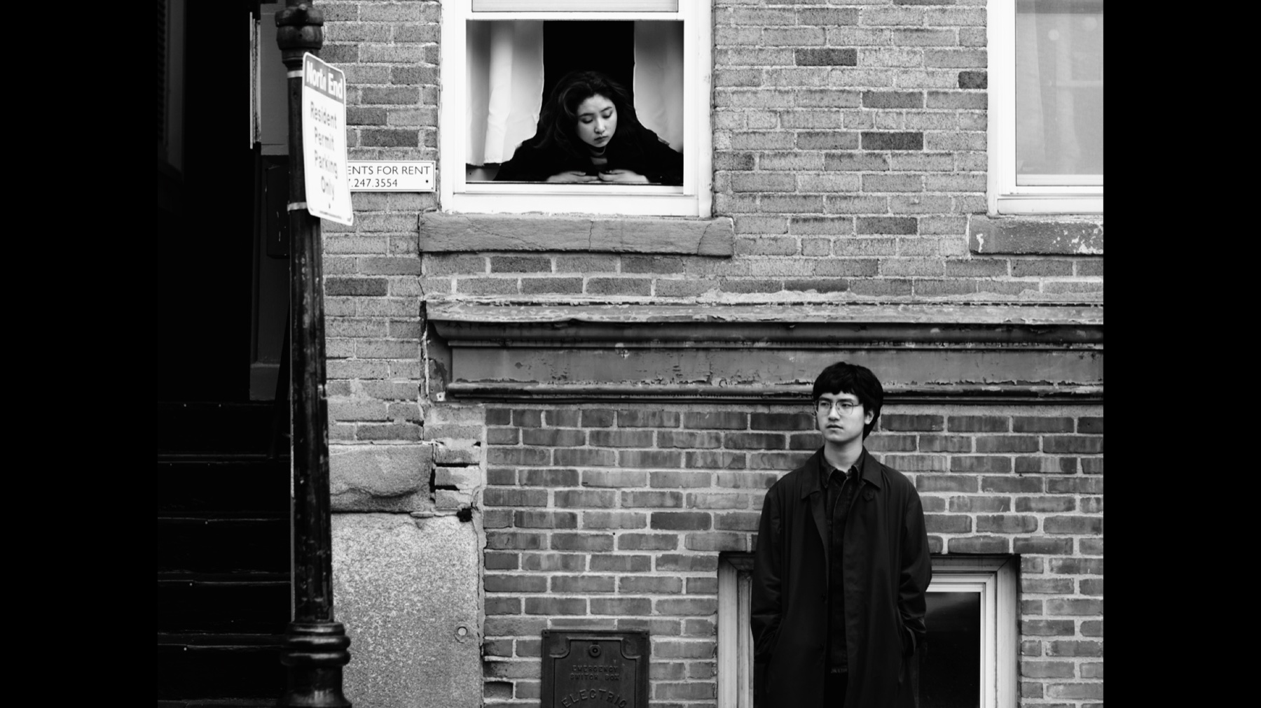 Black-and-white Once Upon the Time in Boston still with Jerry Pan standing below a window